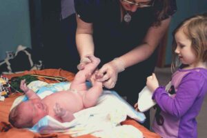 midwife with newborn and sibling